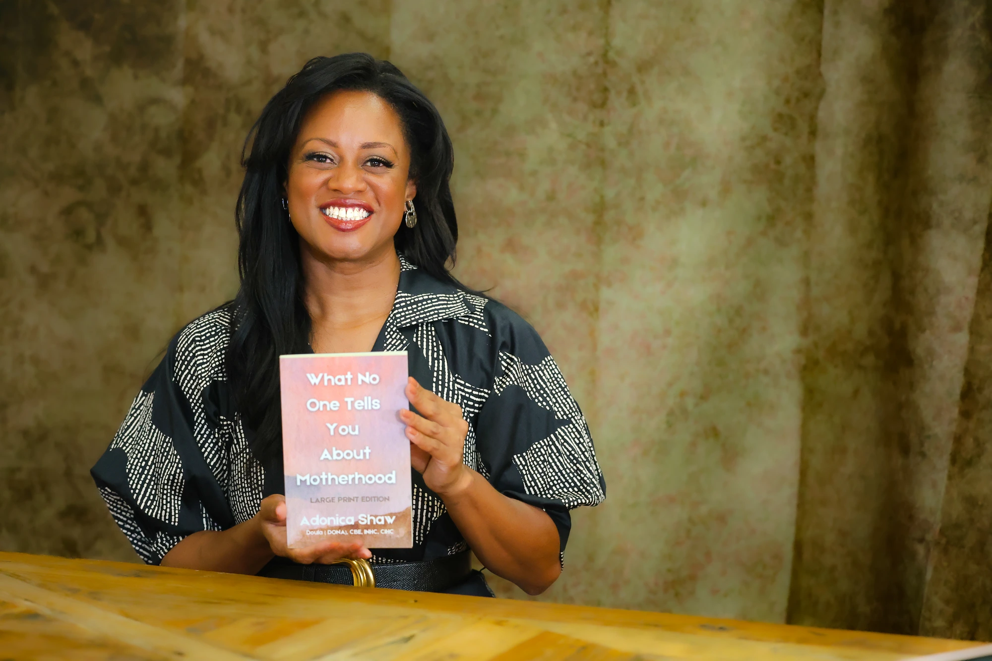 Adonica Shaw holding her book, What No One Tells You About Motherhood